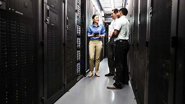 A woman and two men standing and conversing in a data center