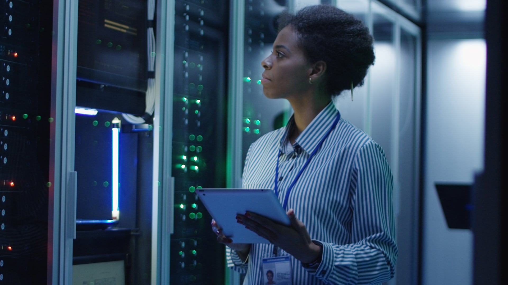 A woman with a tablet working in a data center.