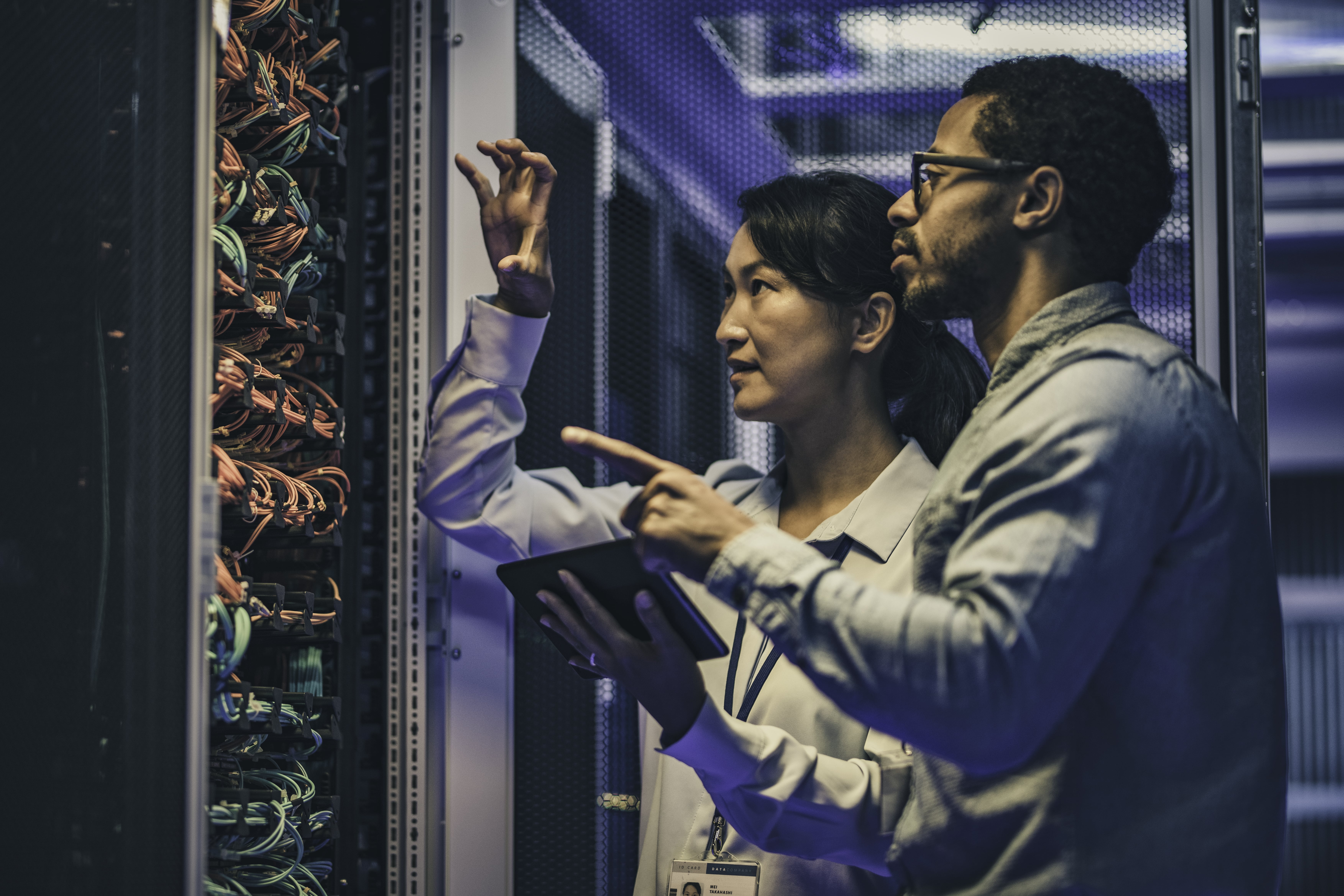 A woman and man in a data center checking optical equipment