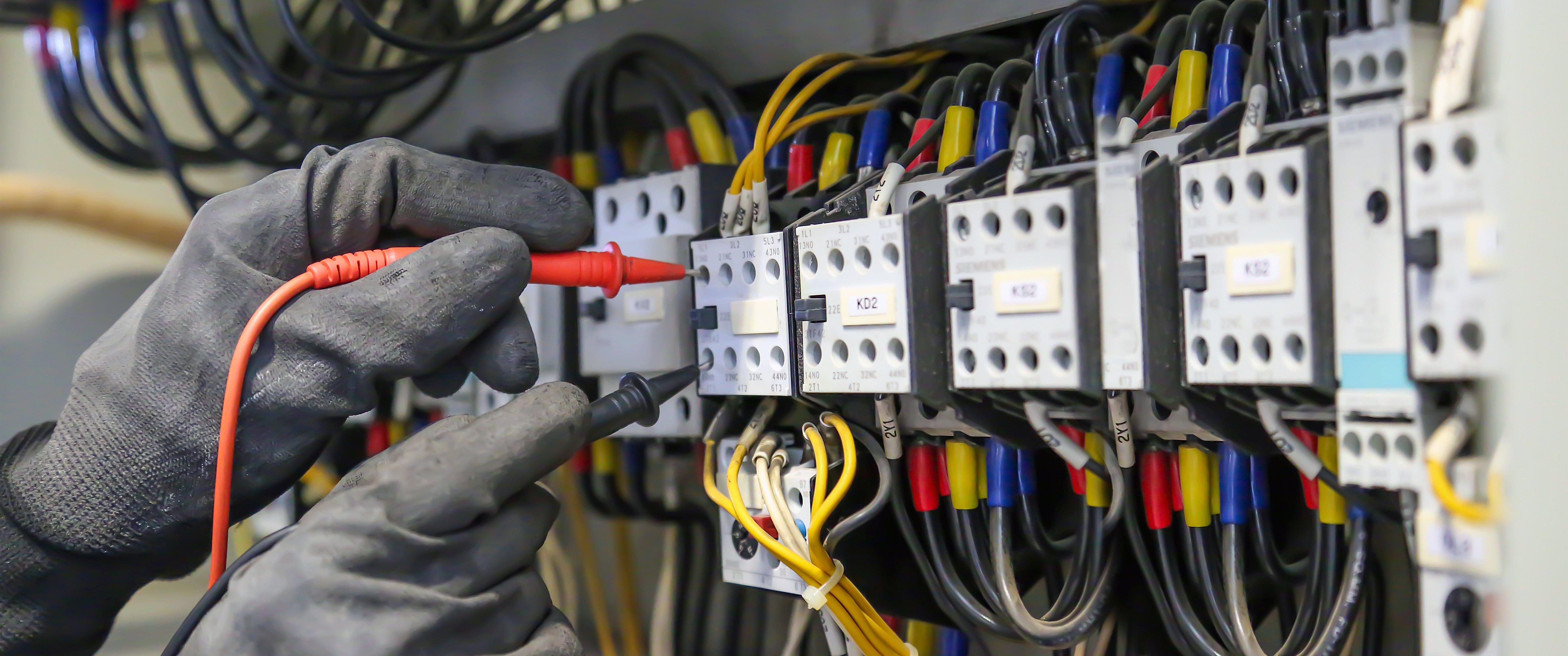 Hands wearing gloves testing the electrical conductivity of data center equipment