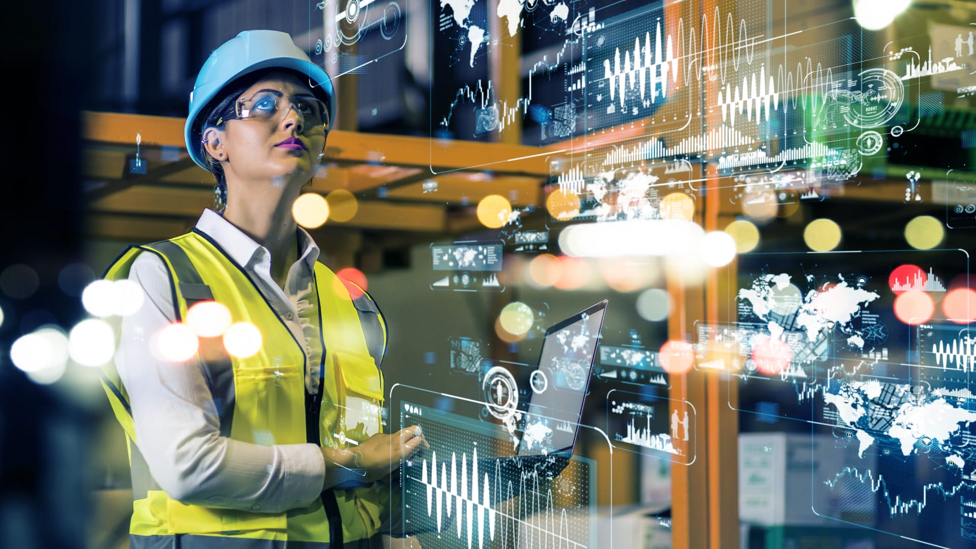 A woman in a hard hat and safety goggles looking up inside a warehouse