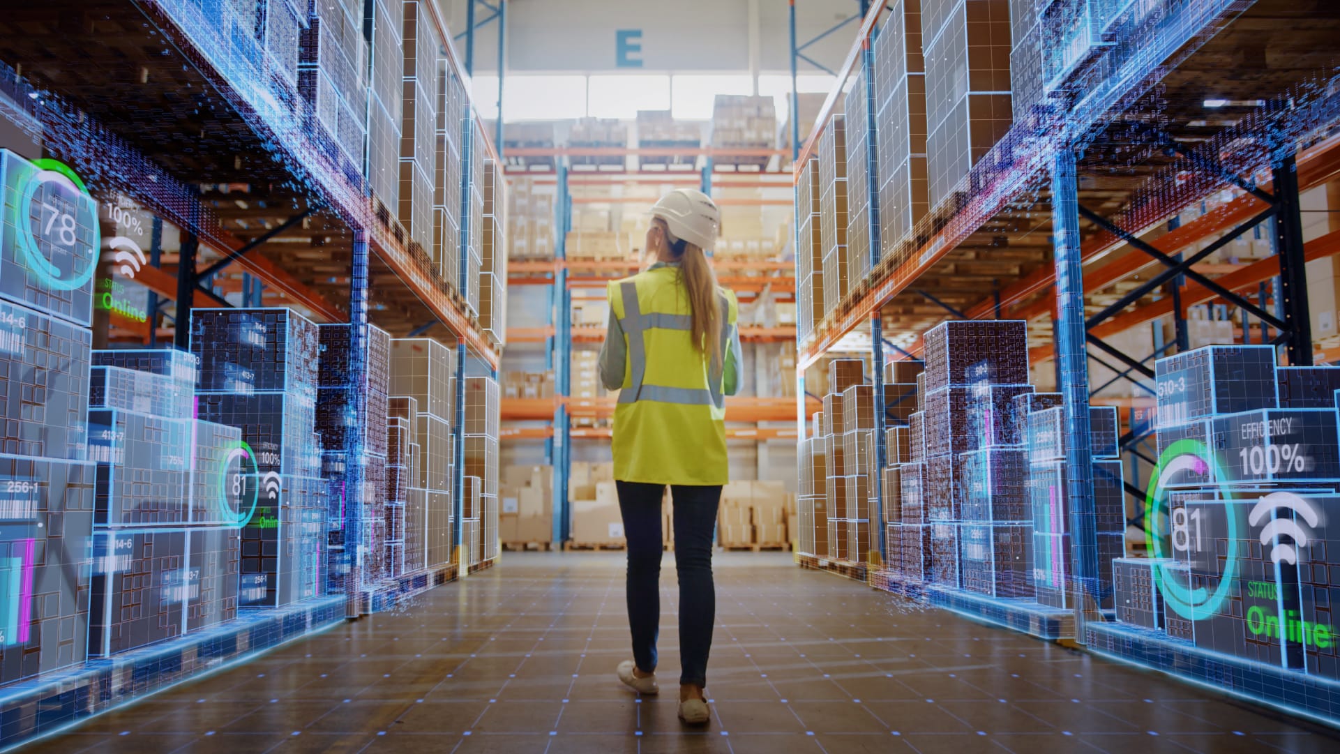 Woman in hard hat walking through warehouse checking inventory