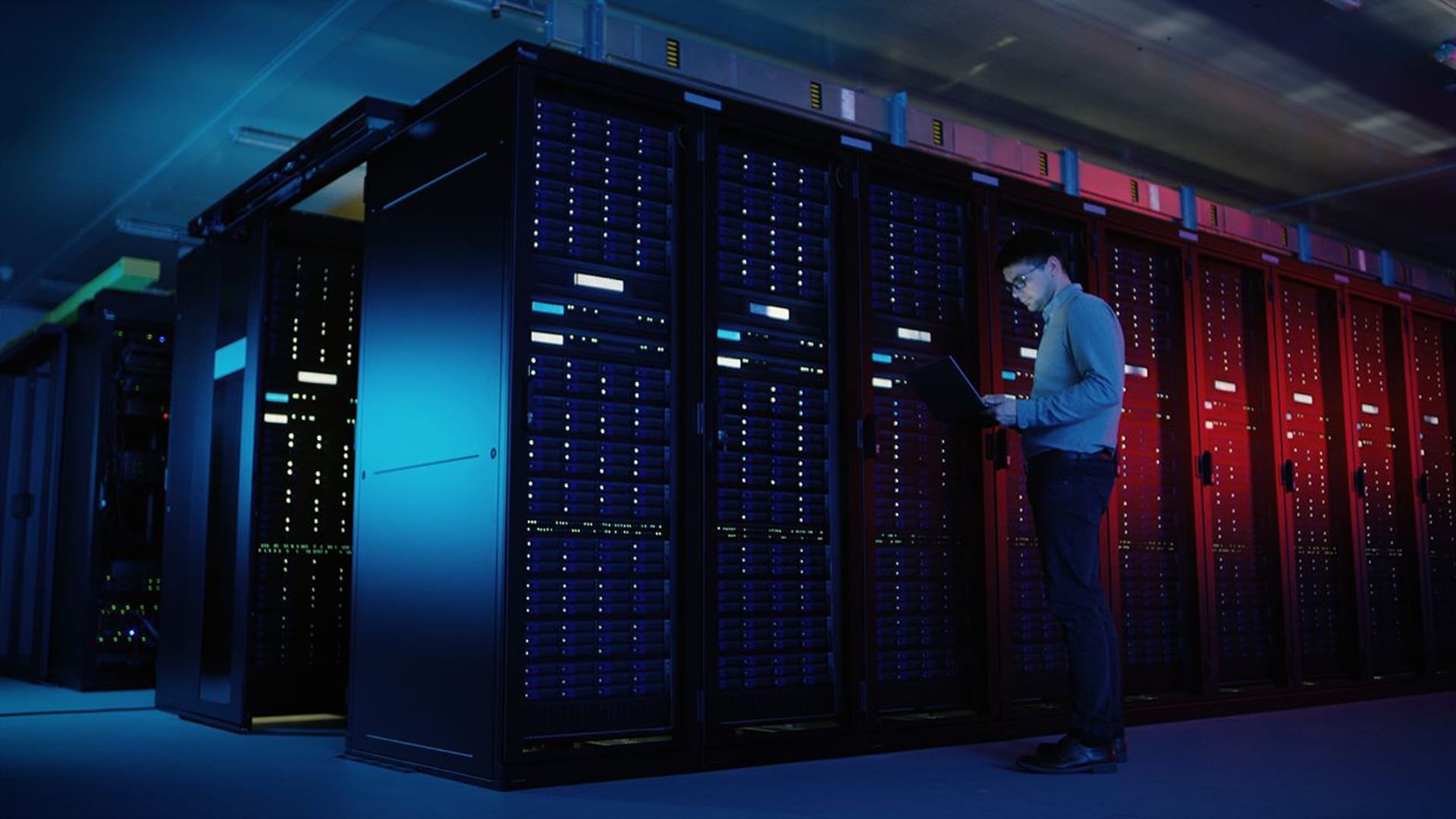 Young man in a data center with blue and red lighting